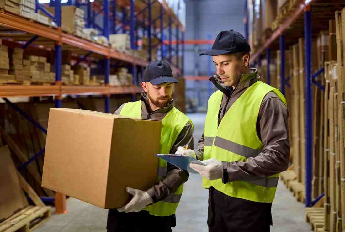 Warehouse workers checking timesheet, representing how Conexis VMS can integrate with any time-clock system - Manufacturing